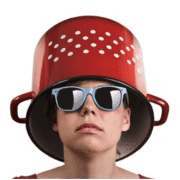 Young person wearing a colander as a hat with sunglasses, symbolizing Fostoria local news coverage.