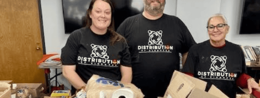 Volunteers in T-shirts with “Distribution” logo sorting food boxes for community pantry.