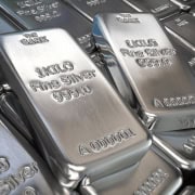 Shiny silver silver bars with inscriptions, stacked closely together.