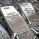 Shiny silver silver bars with inscriptions, stacked closely together.