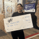 Woman smiling while holding oversized check for HBO donation at Fostoria event.