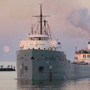 Old steamship docked at harbor during sunset, Fostoria Free Press local news coverage.
