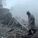 A person standing among rubble and destruction after a disaster or explosion.