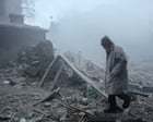 A person standing among rubble and destruction after a disaster or explosion.