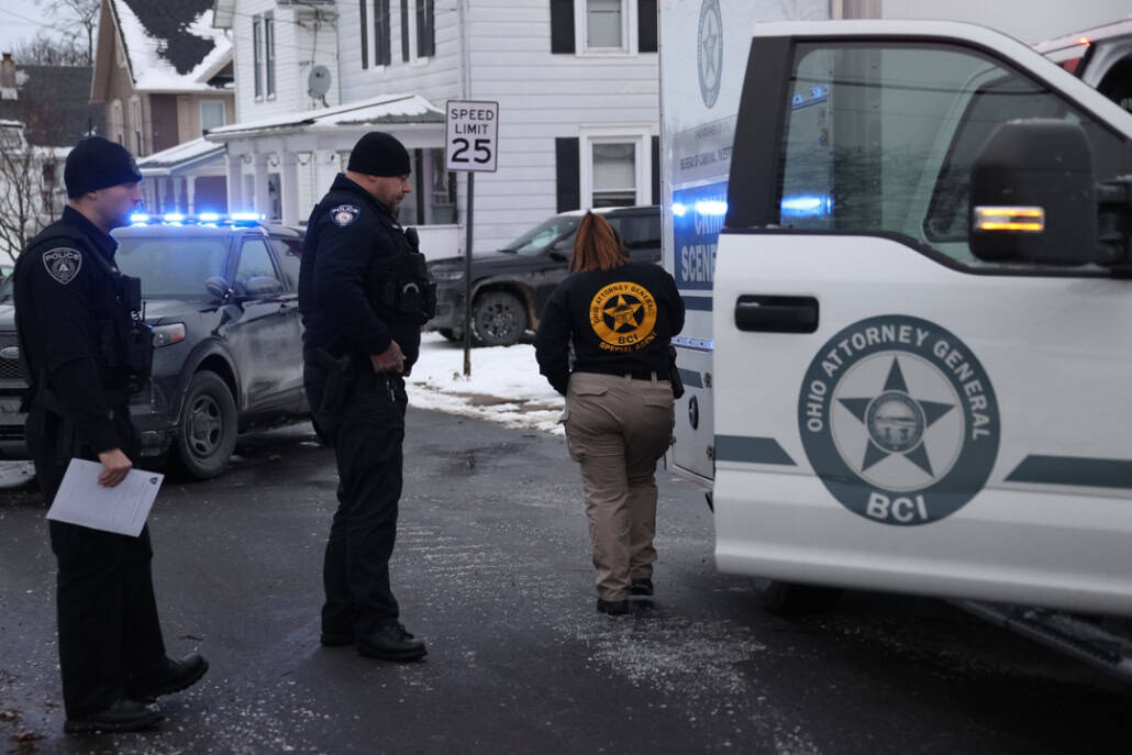 Police officers investigating crime scene with law enforcement vehicles in Fostoria Ohio.