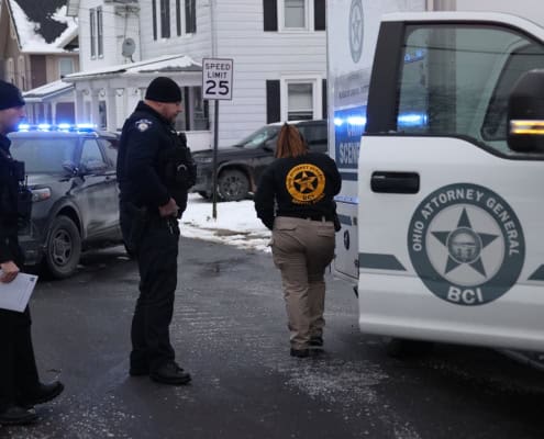 Police officers investigating crime scene with law enforcement vehicles in Fostoria Ohio.