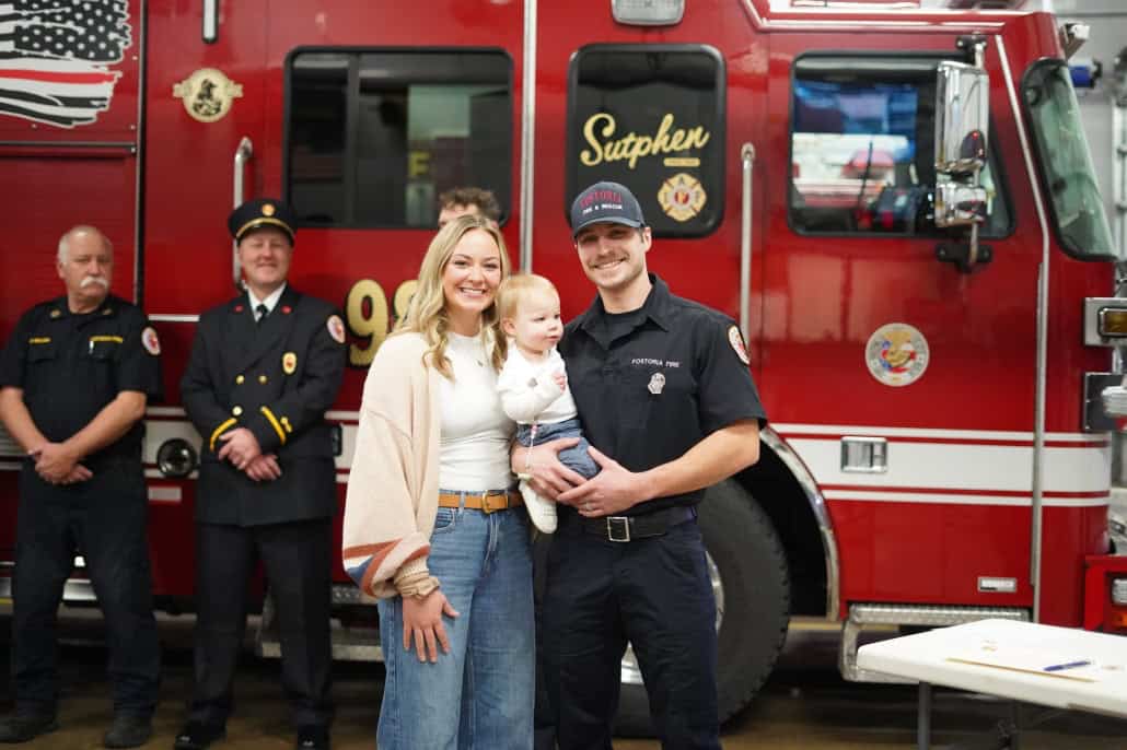 Rescue firefighter with family in front of fire truck at community event.
