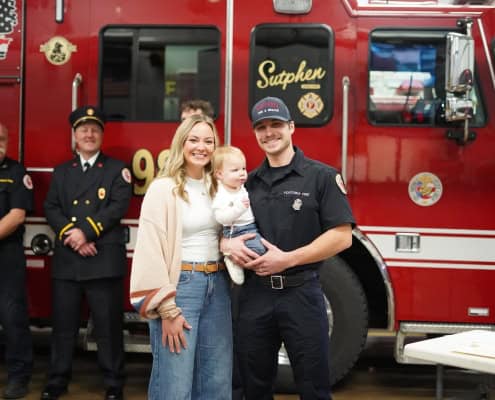 Rescue firefighter with family in front of fire truck at community event.
