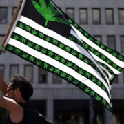 Marijuana flag with cannabis leaf and stripes, urban background.
