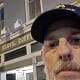Close-up of a man wearing a police cap in front of a coffee shop, highlighting local news and community updates.
