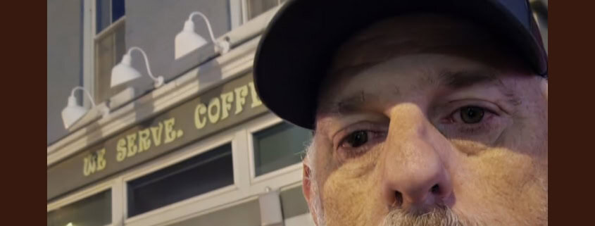Close-up of a man wearing a police cap in front of a coffee shop, highlighting local news and community updates.