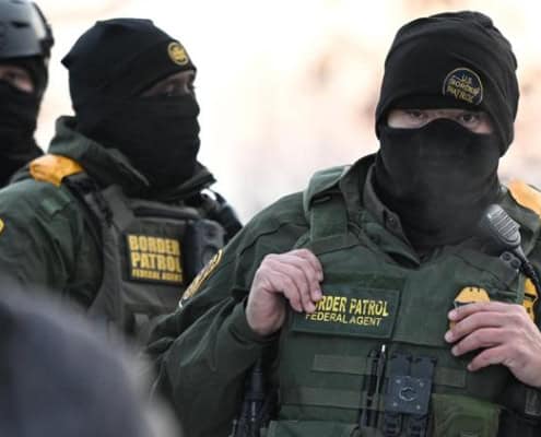 Border patrol agent in tactical gear during law enforcement operation.