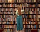 A woman browsing books in a library at The Fostoria Free Press office.