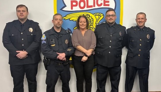 Fostoria News Tiffin Police officers and staff at award ceremony in front of police logo.