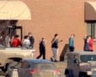 A group of people standing outside a brick building on a sunny day.