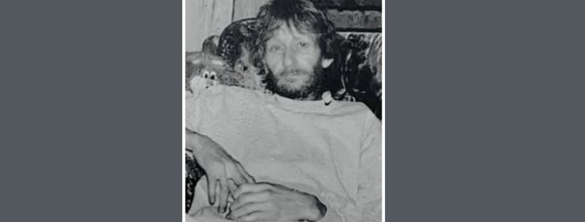 Fostoria News Black and white photo of a man with curly hair and beard sitting on a couch.