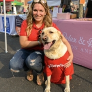 Fostoria News Woman with dog at outdoor event during Downtown Tiffin Third Thursdays.