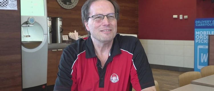 A man in a red and black polo shirt smiling at the camera inside The Fostoria Free Press office.
