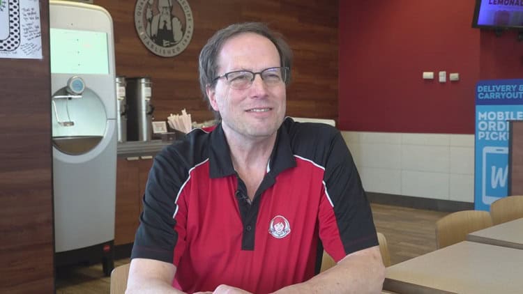 A man in a red and black polo shirt smiling at the camera inside The Fostoria Free Press office.