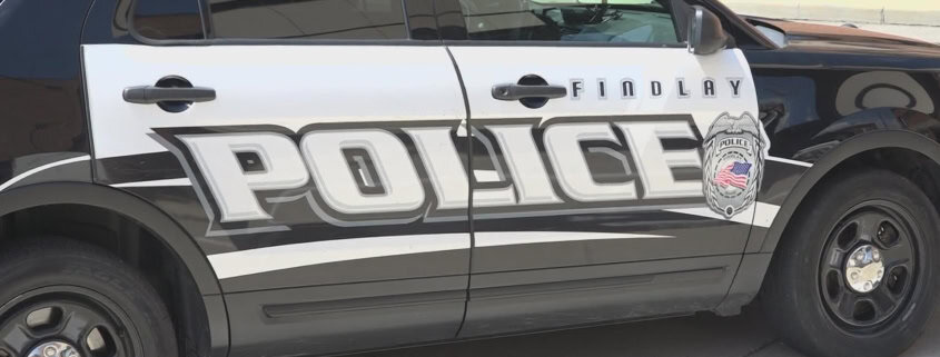 Police car parked on the street with "FINDLAY POLICE" branding and badge logo visible.