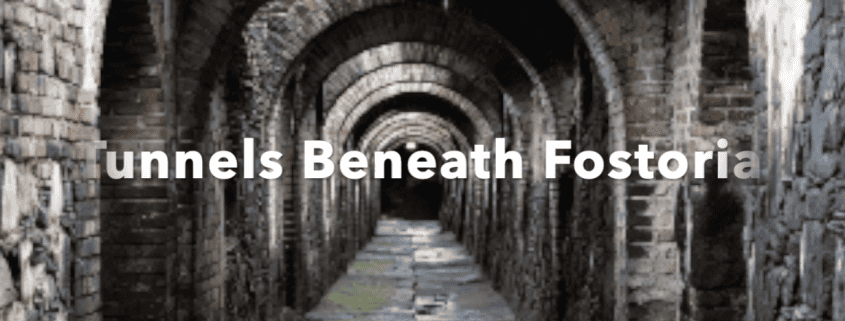 Historic brick tunnels beneath Fostoria with arched ceilings and mossy floors.