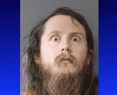 Mugshot of man with long hair and beard, arrested after hidden cameras found in station dressing roo.