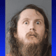 Mugshot of man with long hair and beard, arrested after hidden cameras found in station dressing roo.