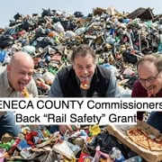 Fostoria News Three men eating pizza in front of a large pile of trash and garbage.