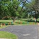 Fostoria News Colorful posts surround a paved area in Jackson Park with trees and blue sky.