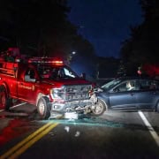 Fire truck and car collision at night on rural road with stop sign.