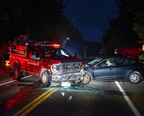 Fire truck and car collision at night on rural road with stop sign.