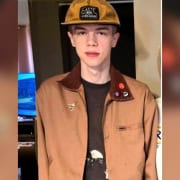 Young man wearing a tan jacket with patches and pins at The Fostoria Free Press event.