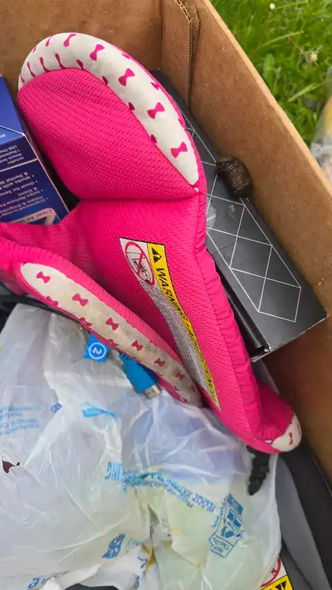 Pink children's backpack with white bone pattern in a cardboard box.