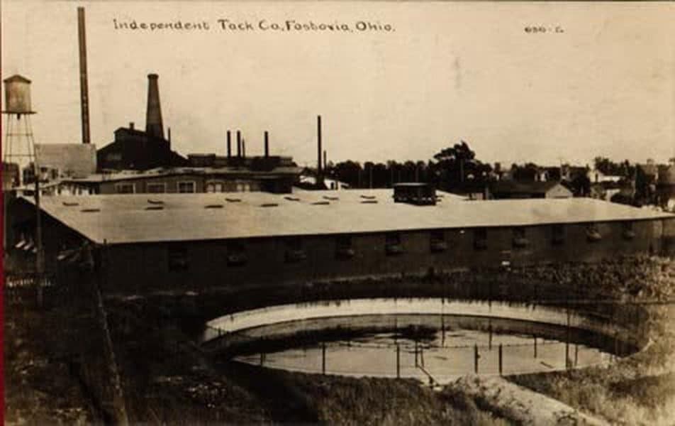 Fostoria News: Real-photo postcard of the Independent Tack Co. factory in Fostoria, Ohio, with smokestacks, a water tower and a round pond in the foreground