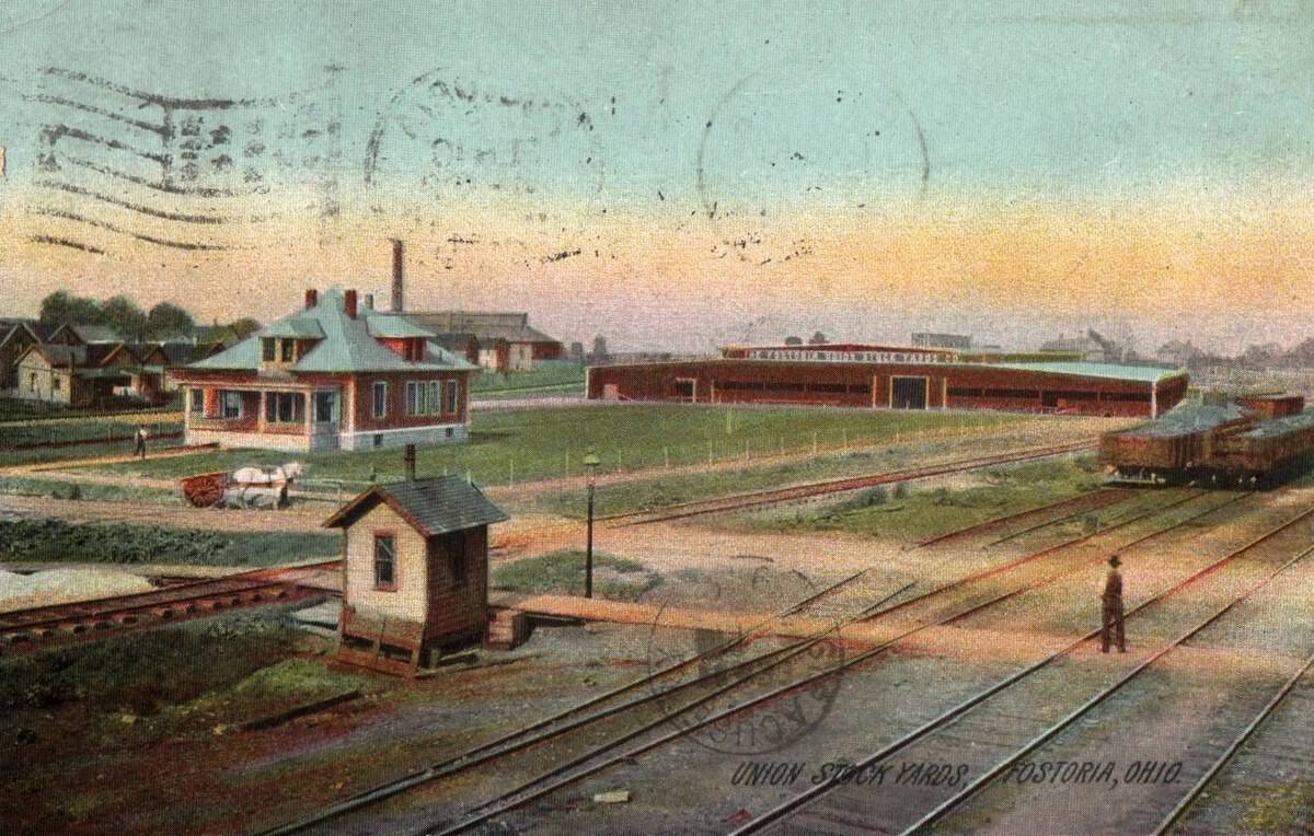 Fostoria News: Color postcard of the Union Stock Yards in Fostoria, Ohio, with rail lines, livestock barns and an office house