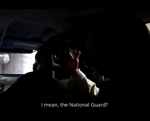 Secretive conversation inside vehicle with subtitles about the National Guard.
