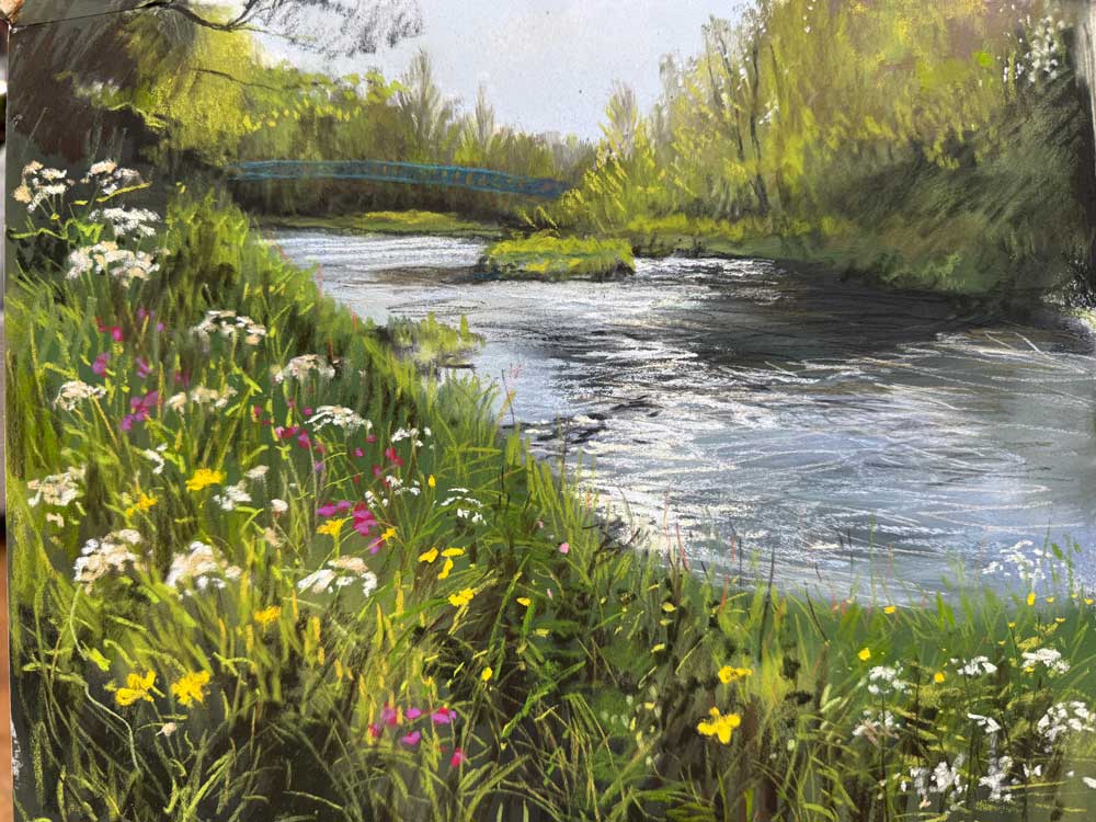 Serene river scene with wildflowers and lush greenery in spring.
