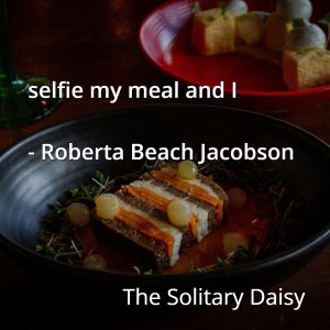 A dark table with a plated gourmet food dish and a red plate of food in the background, overlaid with the quote: "selfie my meal and I - Roberta Beach Jacobson, The Solitary Daisy.