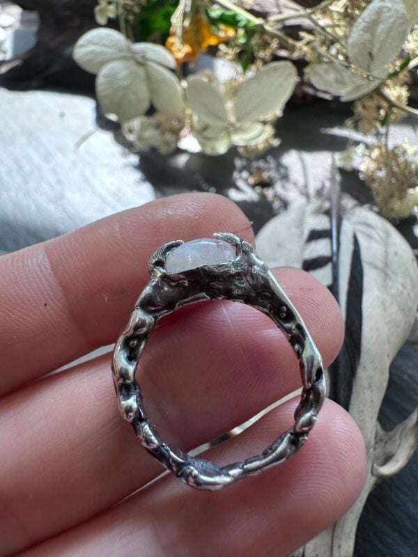 Size 7 rainbow moonstone ring held in hand to show the band and raised claw setting