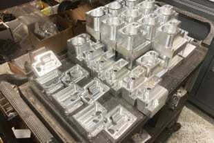 Aluminum engine parts on a workbench at Titan Speed Engineering, showcasing precision machining and high-performance automotive components.