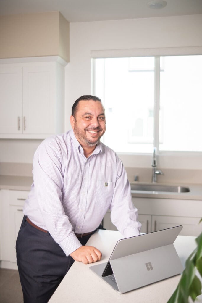 Professional Tony Tadros smiling with Microsoft Surface in a modern kitchen setting - Business Leader.