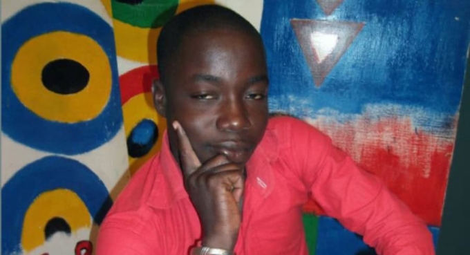 Jeune homme pensif devant un mur coloré au Togo.