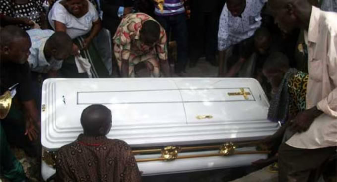 Cérémonie funéraire au Togo avec un cercueil blanc entouré de proches.