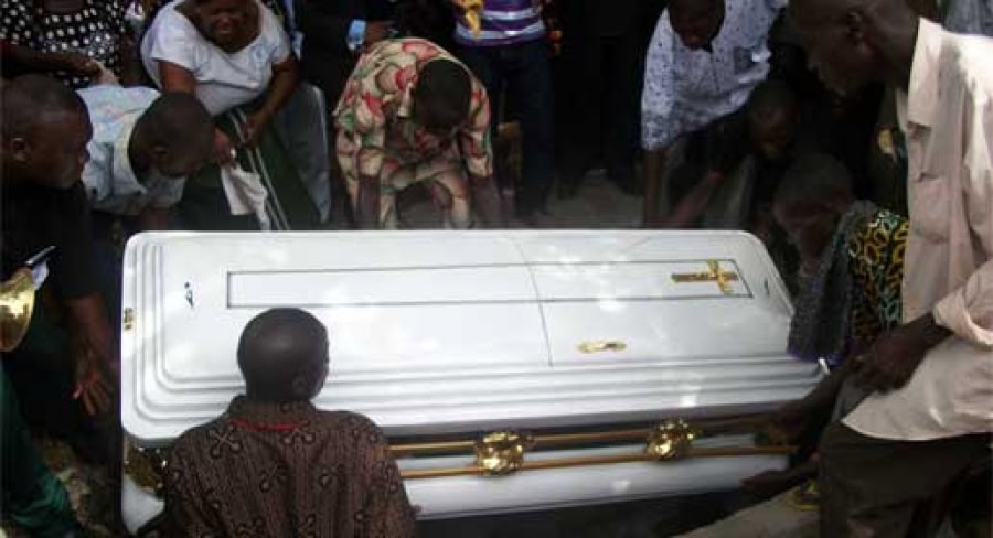 Cérémonie funéraire au Togo avec un cercueil blanc entouré de proches.