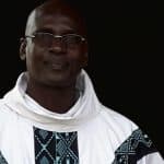 Homme en tenue traditionnelle togolaise avec fond noir.