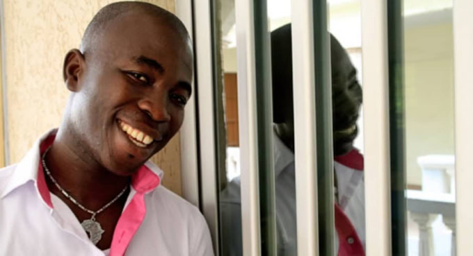 Homme togolais souriant portant une chemise blanche et un collier.