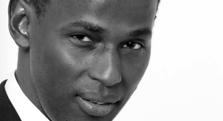 Portrait en noir et blanc d'un homme togolais souriant.