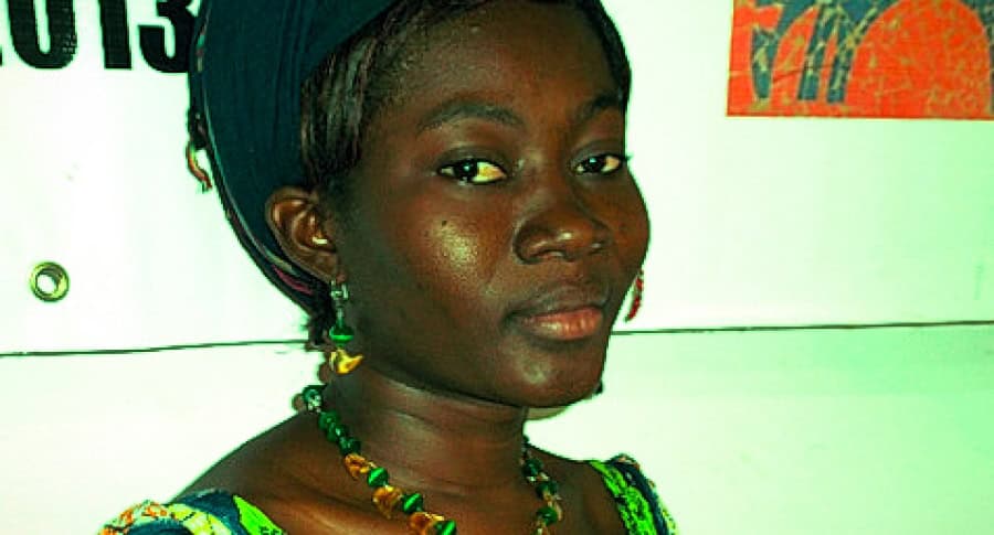 Femme togolaise portant des bijoux traditionnels et vêtue de couleurs vives.