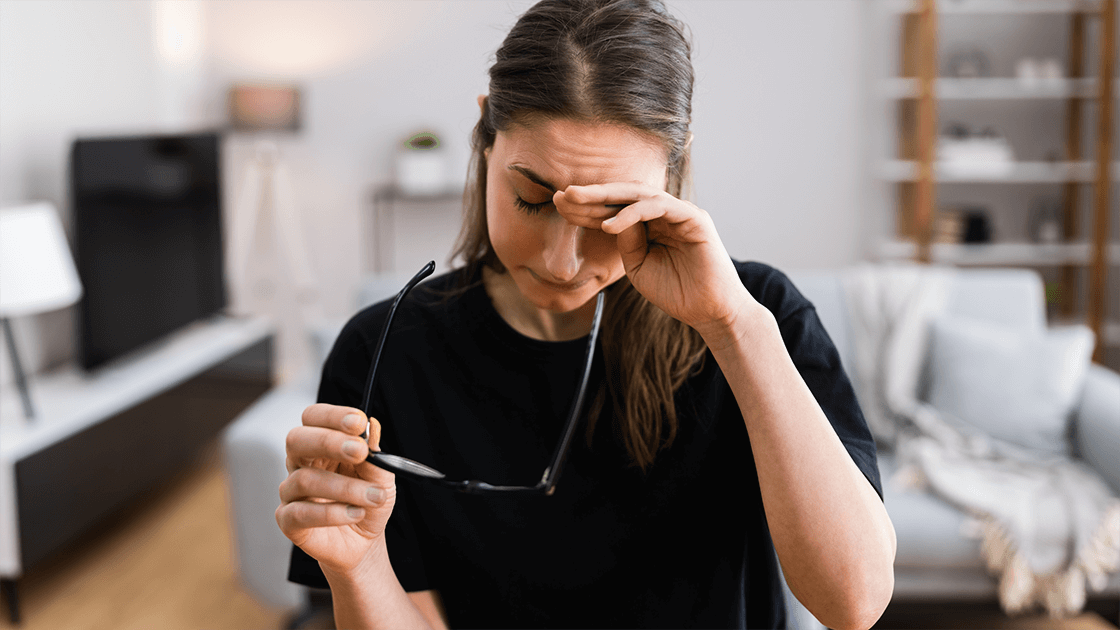 A woman rubbing her eyes, experiencing discomfort and dryness, highlighting the importance of eye care and seeking professional help from an eye doctor, optometrist, or ophthalmologist for dry eye treatment and relief.