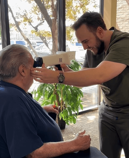 Ryan Jenkins using a handheld retinal scanner on a patient to perform a quick, comfortable, and dilation-free eye examination in the clinic.
